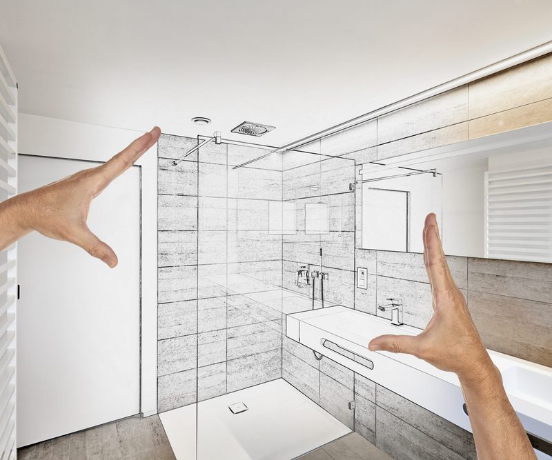 A pair of hands measures a bathroom layout designed by Bathcrest