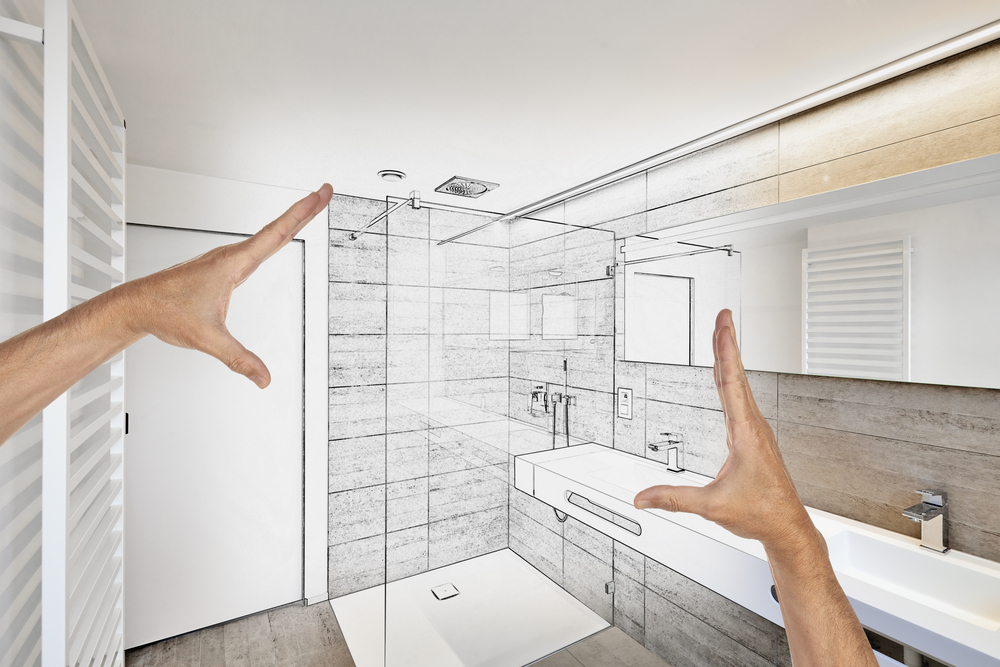 A pair of hands measures a bathroom layout designed by Bathcrest